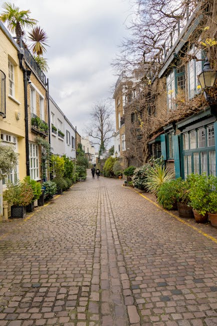 A cobbled residential street in South Kensington with rows of multi-storey houses on either side, featuring a mix of modern and traditional architecture. The buildings have different exterior finishes
